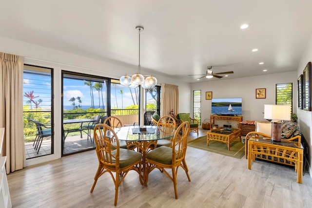 dining area with ceiling fan with notable chandelier and light hardwood / wood-style floors