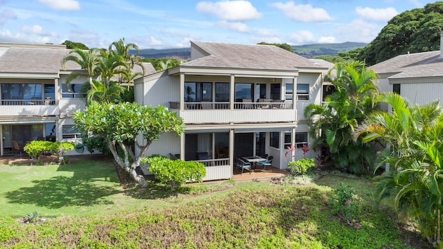 rear view of house with a mountain view and a yard