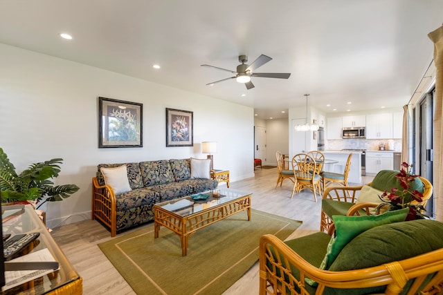 living room featuring light hardwood / wood-style floors and ceiling fan with notable chandelier