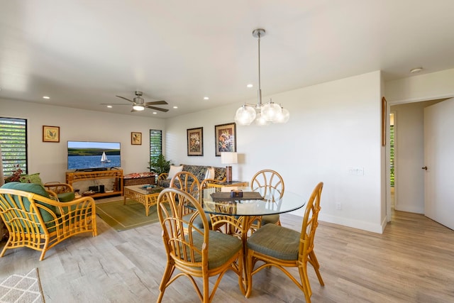 dining area featuring ceiling fan with notable chandelier and light hardwood / wood-style flooring