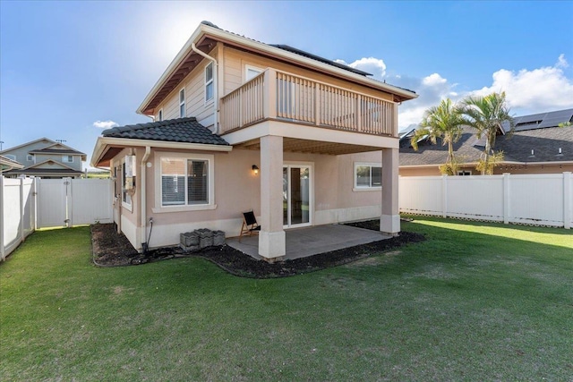 back of house with a balcony, a patio, and a lawn