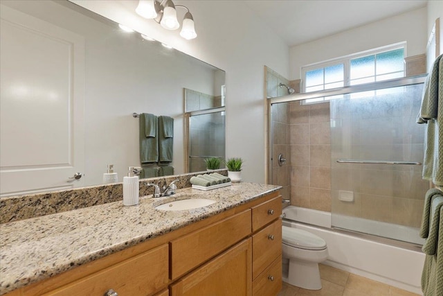 full bathroom featuring tile patterned floors, vanity, bath / shower combo with glass door, and toilet