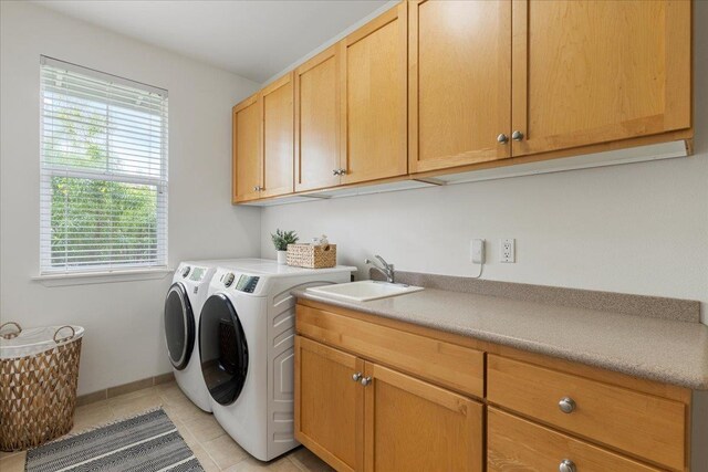 washroom featuring separate washer and dryer, sink, light tile patterned floors, and cabinets