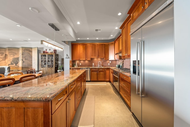 kitchen featuring backsplash, stainless steel appliances, a center island, hanging light fixtures, and light tile patterned flooring