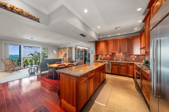 kitchen with a center island, tasteful backsplash, light hardwood / wood-style flooring, decorative light fixtures, and appliances with stainless steel finishes