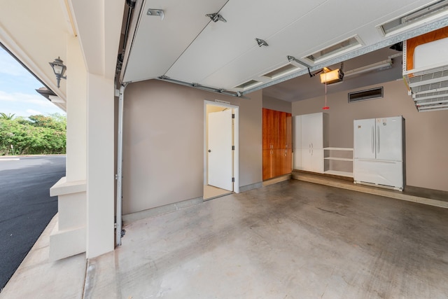 garage with a garage door opener and white refrigerator