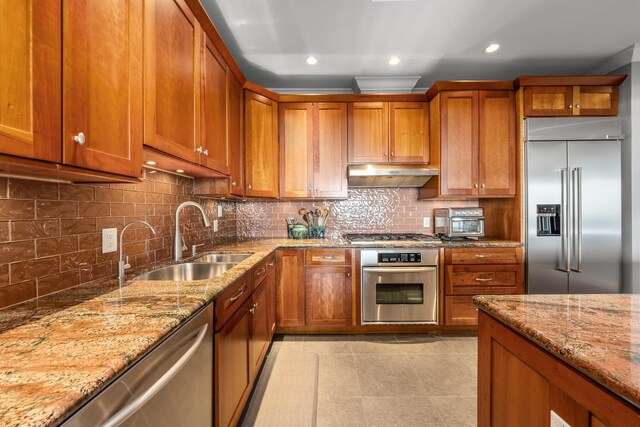 kitchen featuring sink, light stone counters, backsplash, light tile patterned floors, and appliances with stainless steel finishes