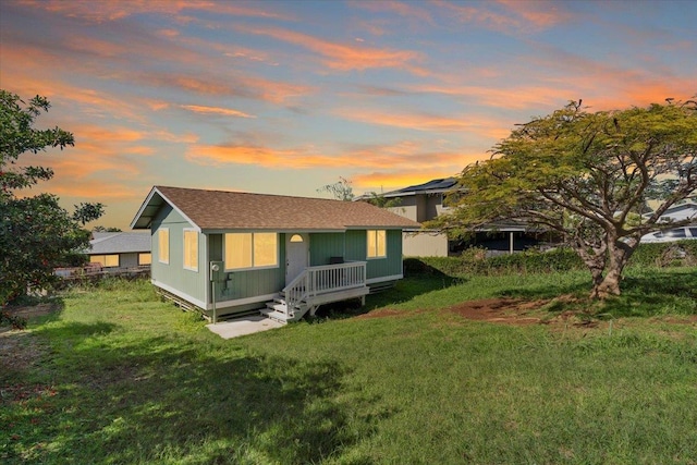 back house at dusk with a lawn