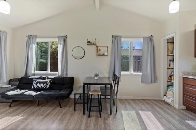 dining area featuring light hardwood / wood-style flooring and vaulted ceiling with beams