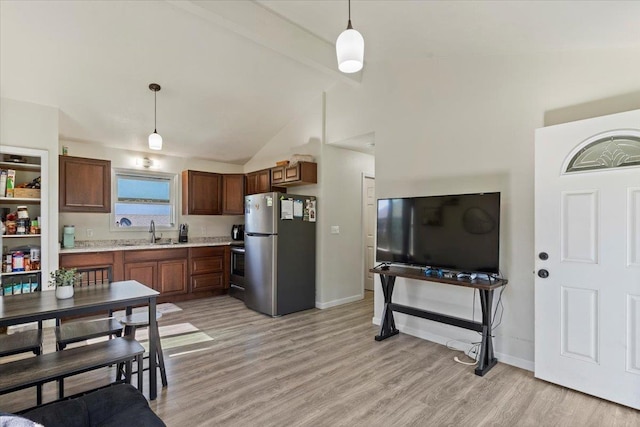 kitchen featuring stainless steel fridge, light wood-type flooring, and decorative light fixtures