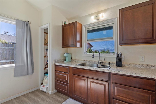 kitchen with sink, a wealth of natural light, light stone countertops, and light hardwood / wood-style floors