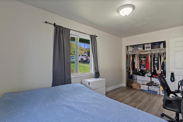 bedroom with wood-type flooring, a textured ceiling, and a closet