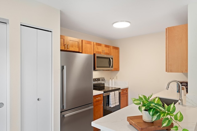 kitchen featuring appliances with stainless steel finishes, a sink, and brown cabinets