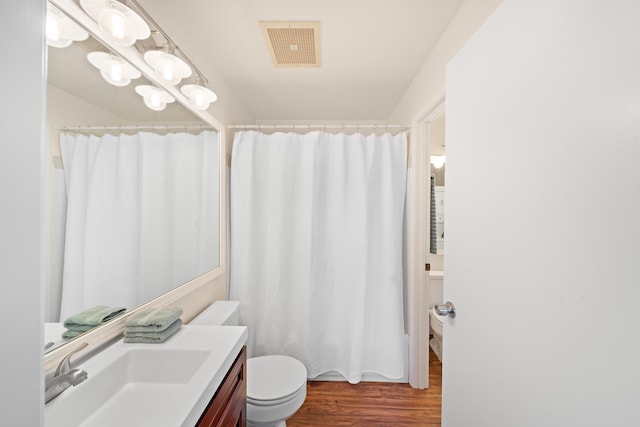 full bath with toilet, wood finished floors, and vanity