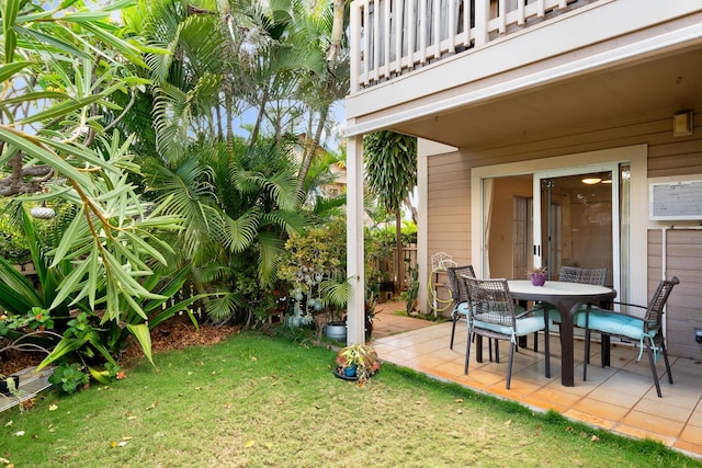 view of grassy yard with a balcony, a patio, and outdoor dining space