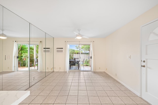 empty room featuring a ceiling fan, healthy amount of natural light, light tile patterned flooring, and a wall mounted air conditioner