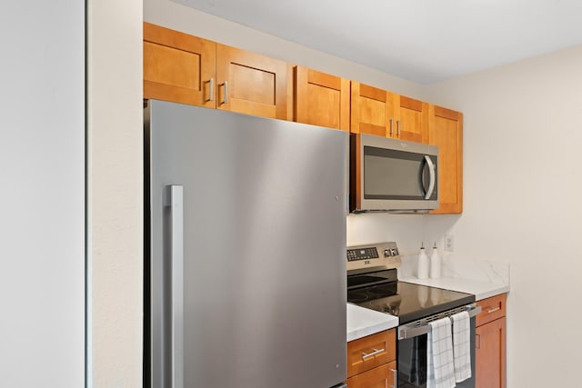 kitchen featuring appliances with stainless steel finishes, light countertops, and brown cabinetry