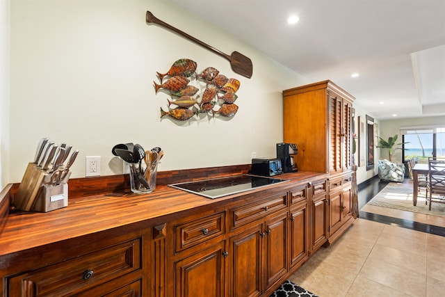 kitchen with black electric cooktop, butcher block counters, and light tile patterned floors