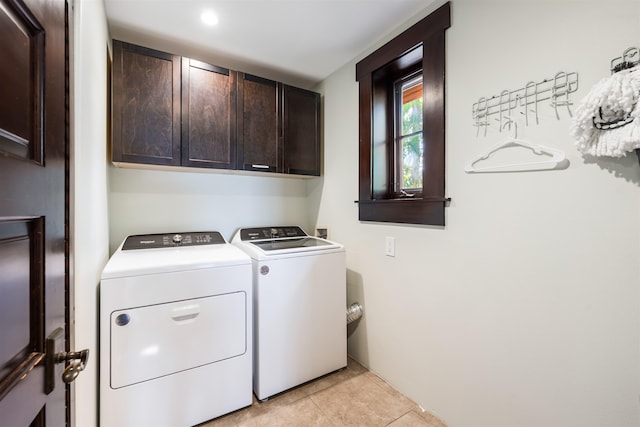 clothes washing area with cabinets, light tile patterned flooring, and independent washer and dryer