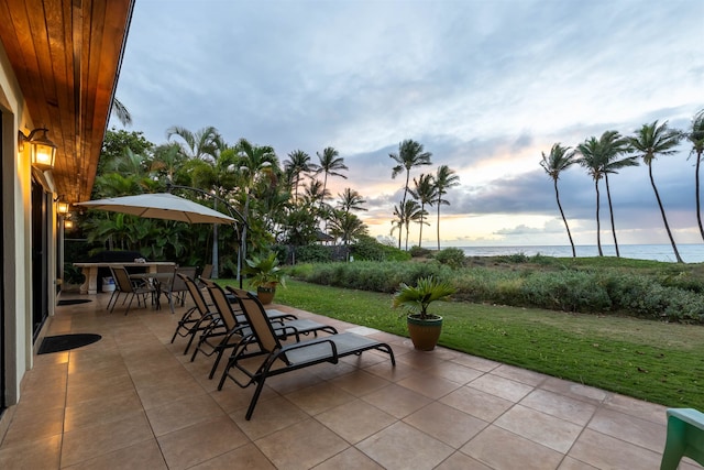 patio terrace at dusk with a water view and a lawn