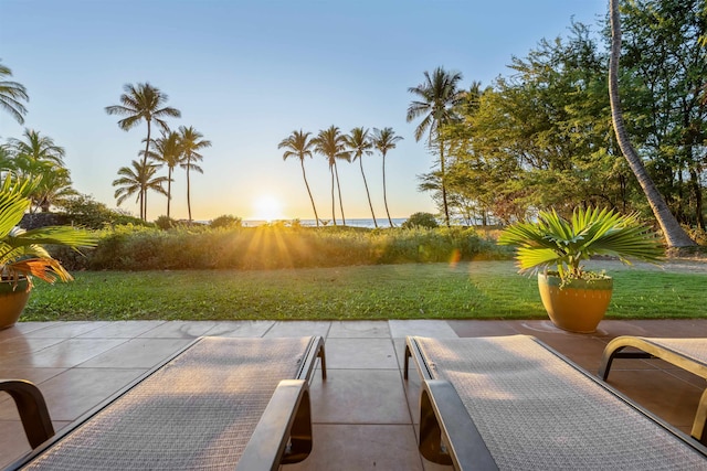 patio terrace at dusk featuring a lawn