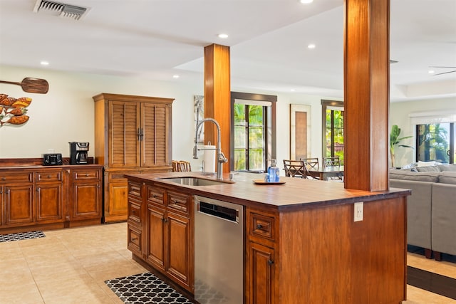 kitchen featuring sink, a kitchen island with sink, decorative columns, light tile patterned flooring, and stainless steel dishwasher