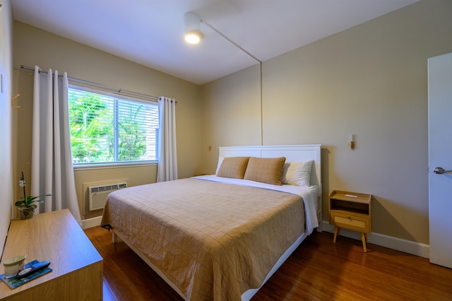 bedroom with dark hardwood / wood-style floors and an AC wall unit