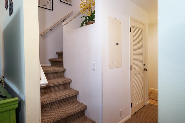 staircase featuring electric panel and tile patterned flooring