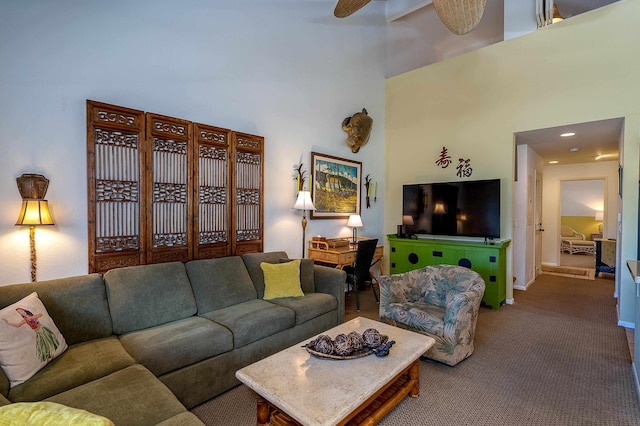 carpeted living room featuring a towering ceiling and ceiling fan