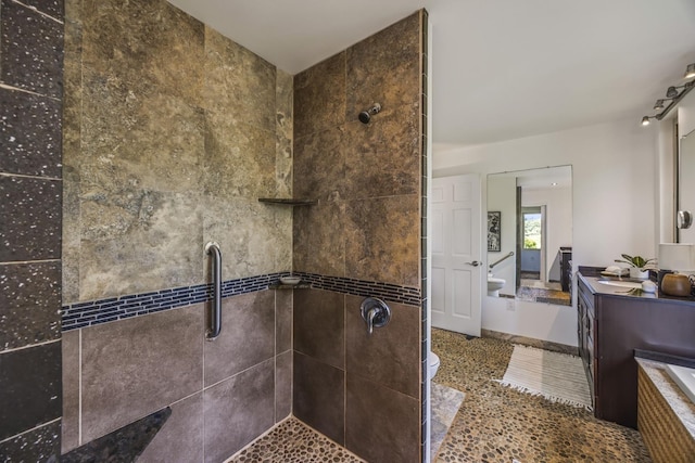 bathroom featuring tiled shower, toilet, and vanity