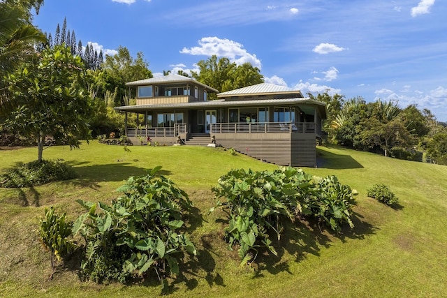 rear view of property featuring metal roof, a lawn, and a porch