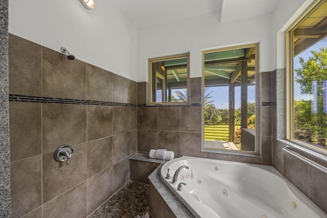 bathroom featuring a jetted tub, a wealth of natural light, and tiled shower