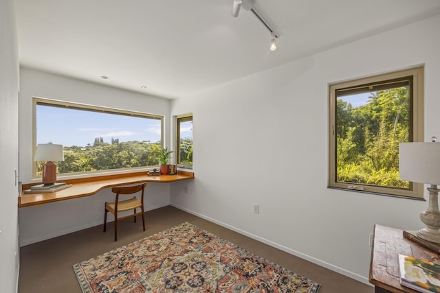office area featuring baseboards, concrete flooring, track lighting, and built in desk