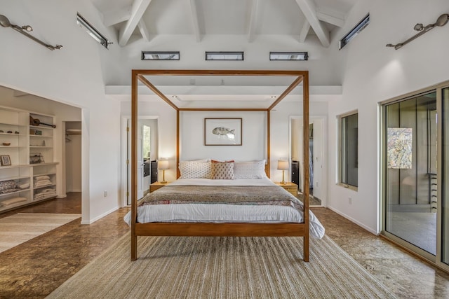 bedroom with a walk in closet, beamed ceiling, baseboards, and a high ceiling