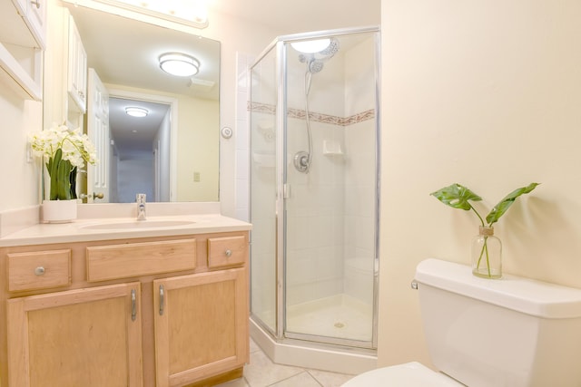 bathroom featuring vanity, toilet, a shower with shower door, and tile patterned flooring