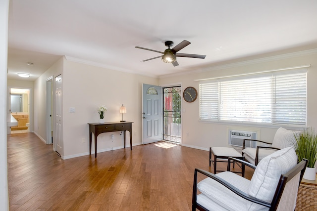 living area with an AC wall unit, hardwood / wood-style flooring, ornamental molding, and ceiling fan