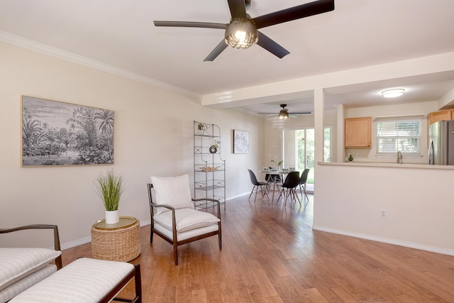 sitting room with crown molding, hardwood / wood-style flooring, sink, and ceiling fan