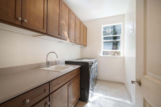 clothes washing area featuring cabinet space, light tile patterned floors, baseboards, separate washer and dryer, and a sink