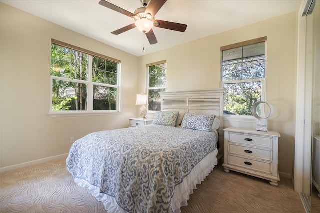 bedroom with a ceiling fan, carpet flooring, multiple windows, and baseboards