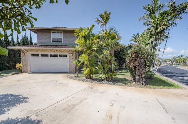 view of front facade featuring an attached garage, stone siding, and concrete driveway