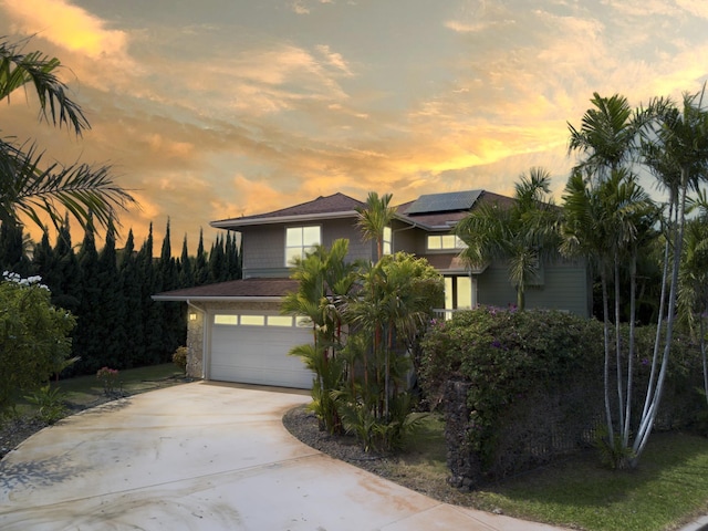 view of front facade with a garage, roof mounted solar panels, and concrete driveway