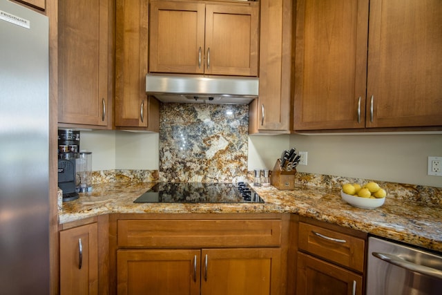 kitchen featuring stainless steel appliances, brown cabinetry, under cabinet range hood, and light stone countertops