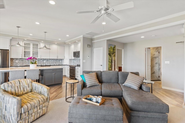 living room featuring ceiling fan, light wood-type flooring, and crown molding