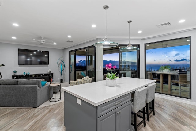 kitchen featuring gray cabinetry, ceiling fan, crown molding, decorative light fixtures, and light wood-type flooring