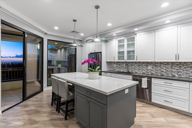 kitchen with white cabinetry, sink, hanging light fixtures, a kitchen island, and appliances with stainless steel finishes