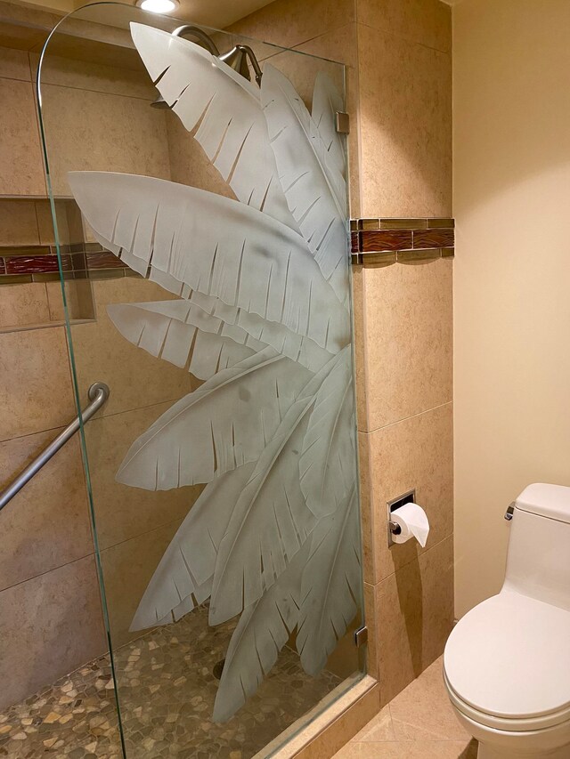 bathroom with toilet, walk in shower, tile patterned floors, and tile walls