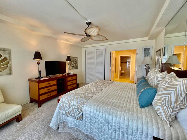 carpeted bedroom featuring a closet, ensuite bathroom, and ceiling fan