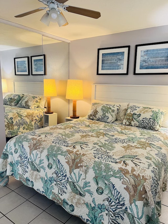 tiled bedroom with ceiling fan and a closet