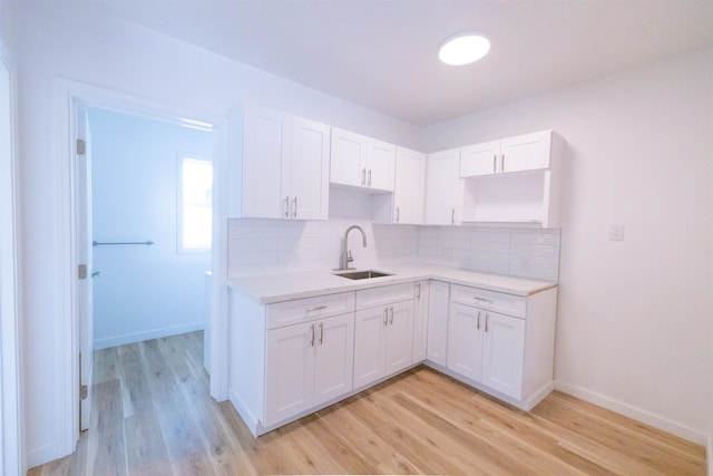 kitchen featuring white cabinetry, sink, tasteful backsplash, and light hardwood / wood-style floors