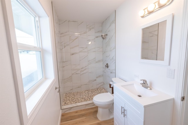 bathroom with vanity, hardwood / wood-style flooring, toilet, and tiled shower